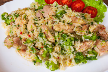 chicken meat with rice and vegetables in a plate on wooden table