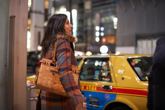 Side view of mature woman carrying handbag on shoulder waiting to cross road, Ginza, Tokyo, Japan