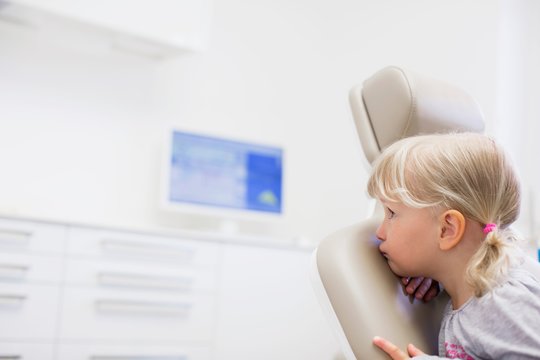 Girl sitting backwards in dentist chair looking away