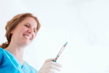 Low angle view of dental nurse wearing protective gloves holding syringe smiling