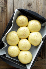 bread buns on a baking sheet on a wooden table