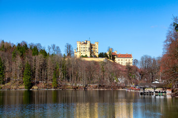 Fototapeta premium Hohenschwangau Castle, Alpsee lake, landscape view in spring, red maple fall foliage, Bavaria, Germany