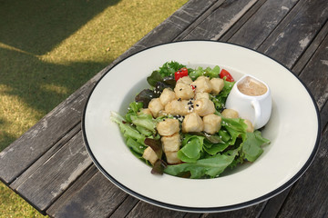 Fried tofu salad dish is placed on the wooden table in the garde