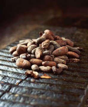 Raw cocoa beans on a ridged wooden board, close-up