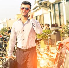  Handsome man talking on mobile phone on street next to sport car - Concept of self confidence and successful life style - 
