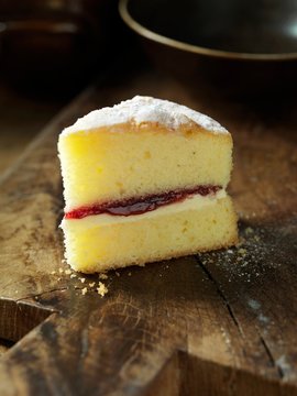 Gluten free Victoria sponge cake, jam, cream, wooden chopping board