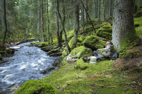 Boy relaxing by stream in forest