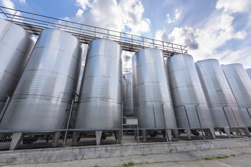 Metal wine barrels at a winery and blue sky with white clouds