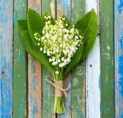 Photo sur Plexiglas Muguet bouquet de fleurs de muguet avec des feuilles vertes attachées avec de la ficelle dans des gouttelettes d& 39 eau sur des planches de bois avec des restes de peinture ancienne