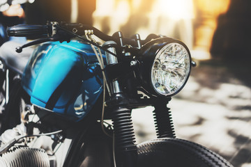 Close-up of a vintage cafe-racer motorcycle, details of hipster motorbike outdoors, flare light,...