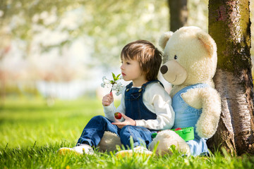 Cute little boy, eating strawberry in the park on a spring sunny