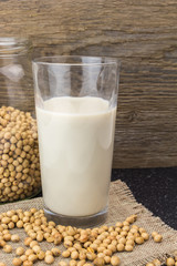 Soybeans and glass of soy milk, on wooden background.