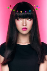 Attractive asian descent girl with dark haircut on the pink background