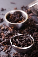 Strainer and metal bowl full of dry tea leaves