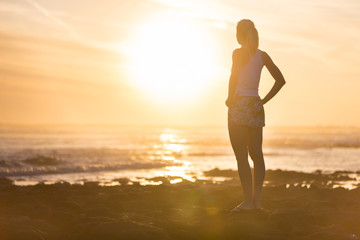 Silhouette of meditative, sensual blonde woman watching sunset at the beach.