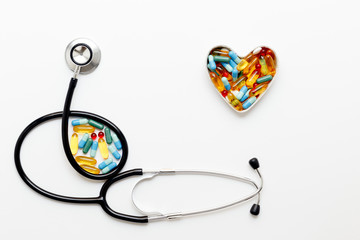 stethoscope on white background with pills in shape of heart