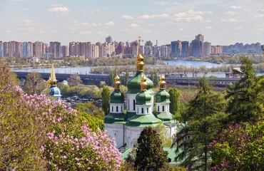 Deurstickers St. George-kathedraal van het Vydubychi-klooster tussen de bomen van het park tegen de lente van moderne flatgebouwen. Kiev, Oekraïne. © Dmytro Kosmenko