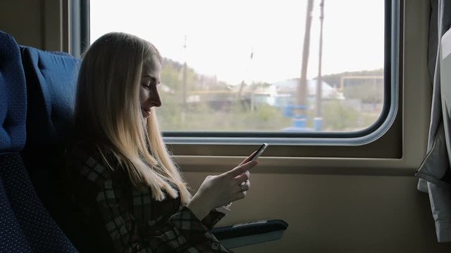 Young woman using smartphone while traveling by train