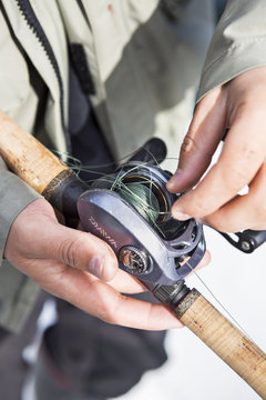 Man untangling fishing line on reel, close-up