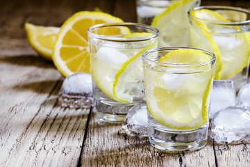 Lemon vodka with ice, vintage wooden background, selective focus