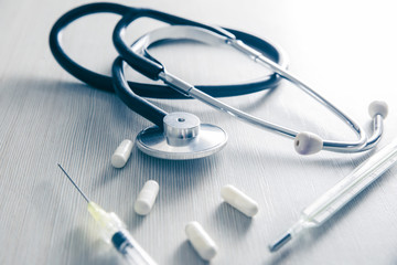 still life about medicine subjects a stethoscope, a thermometer and pills in blue color