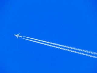 Airplane with chemtrails on blue sky