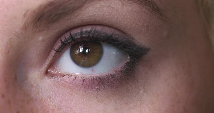 Big close up of a woman's brown eye looking at the camera and looking around.  High contrast look, recorded in 4K at 60fps.