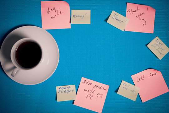 Cup of coffee and stickers with reminders on a blue background