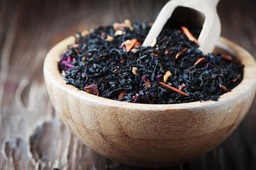 Delicious black tea with petals on the wooden table