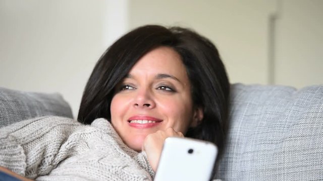 Portrait of woman in sofa using smartphone