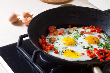 Fried egg, pepper, basil and onion on a pan