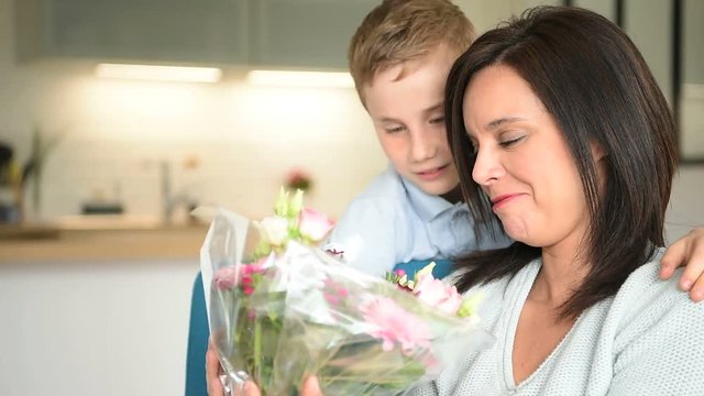 Young boy giving flowers to his mom