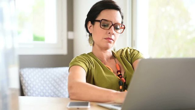 Trendy businesswoman relaxing in front of laptop