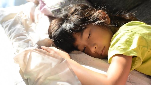 Asian girl sleeping on bed with warm light window in the morning 