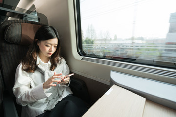 Beautiful asian girl using smartphone while travelling on the train, communication concept