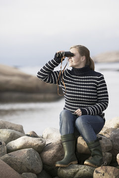 Woman looking at sea through binoculars