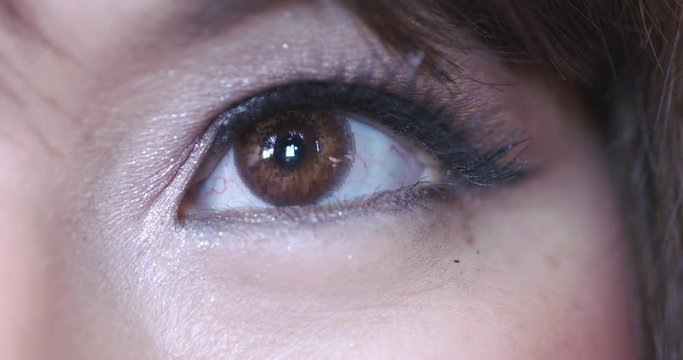 Big close up of Asian woman's left eye with contact lens visible as she looks at the camera and looks around. Recorded in 4K at 60fps.