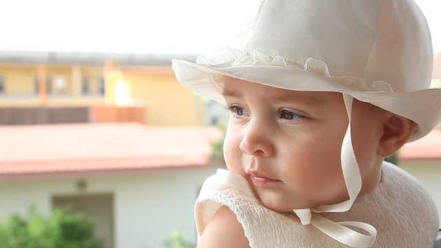 Portrait of a child a few months with white dress and hat on the day of her baptism.