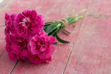 Bouquet of purple carnations on pink wooden background