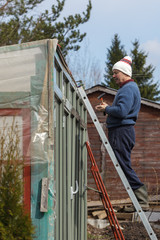 man builds greenhouse improvised from different material