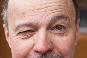 Elderly man with a mustache, winking with one eye