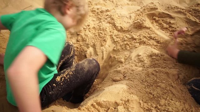 Brothers burrowing hole in sand in Oleshky sands.Ukraine. Slow motion