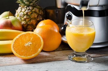 Fresh juice and juicer. Photo on wooden background