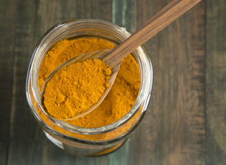 turmeric powder in a glass jar on wooden background