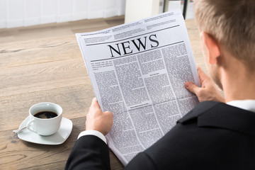 Naklejka premium Businessman Reading Newspaper In Office
