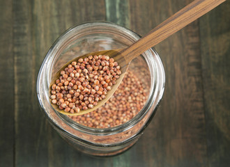 Sorghum in a glass jar on wooden background