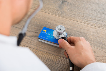Doctor Hand Holding Medical Stethoscope On Credit Card Stack