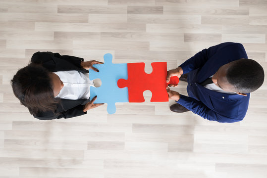 Business Man And Woman Holding Puzzle Pieces