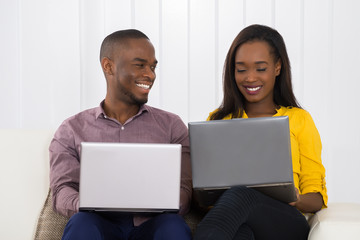 Happy Couple Using Laptops