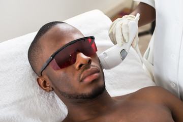 Therapist Giving Laser Epilation Treatment On Young Man